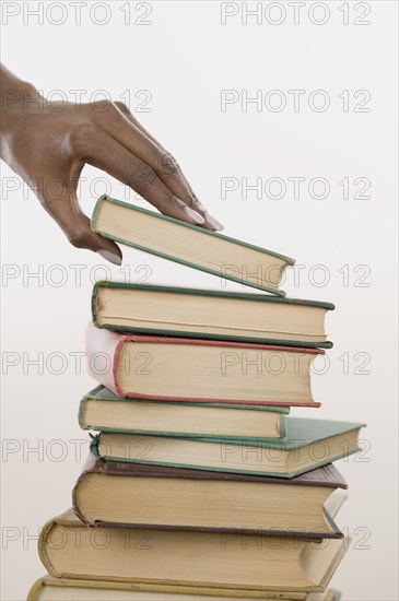 Close up of hands picking up book off stack