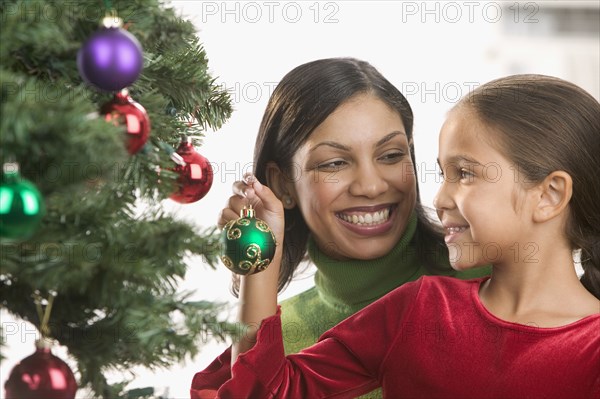 Mother and daughter decorating Christmas tree