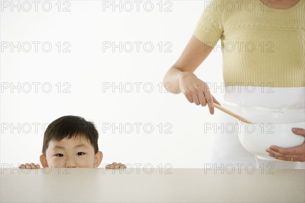 Boy watching mother with mixing bowl