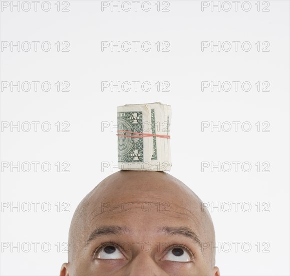 Man with roll of dollar bills on head