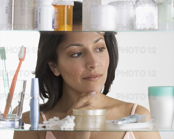 Young woman examining medicine cabinet