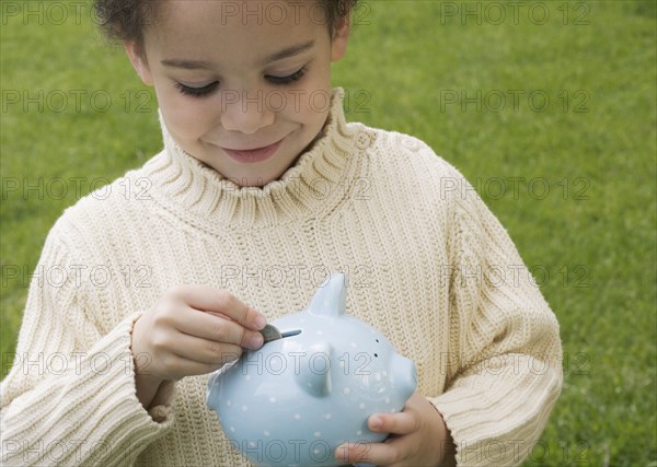 Boy putting money in piggy bank