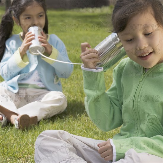 Two girls using tin cans for telephone