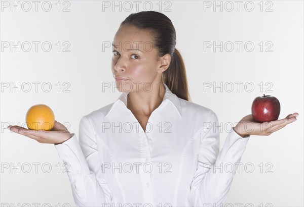 Portrait of woman balancing orange and apple in hands