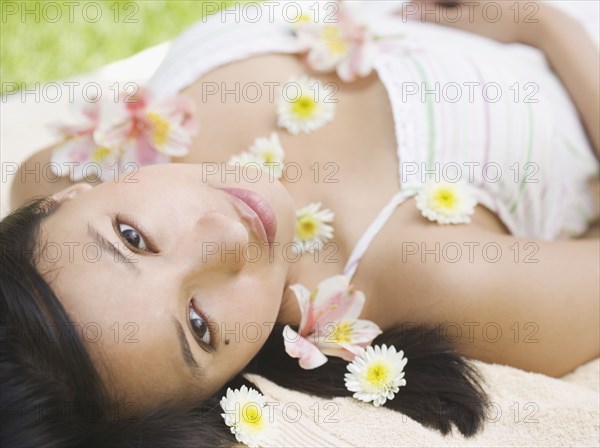 Portrait of woman laying with flowers sprinkled over body