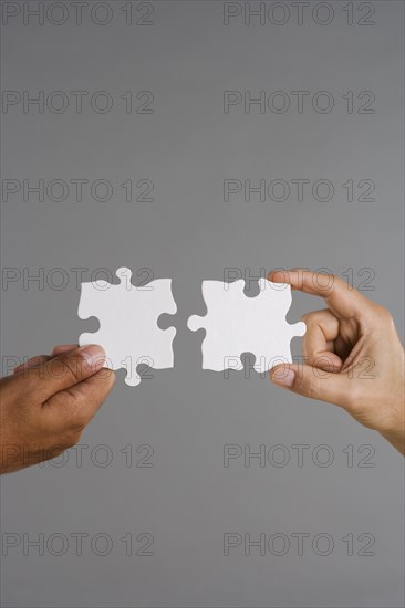 Close up of two hands holding puzzle pieces