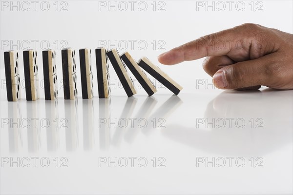 Close up of hand knocking dominos over