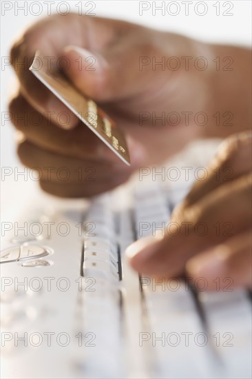 Close up of hands typing on keyboard and holding credit card