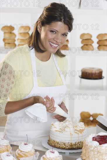 Portrait of woman decorating cake at bakery