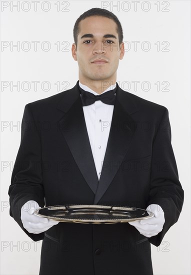 Portrait of male waiter holding tray