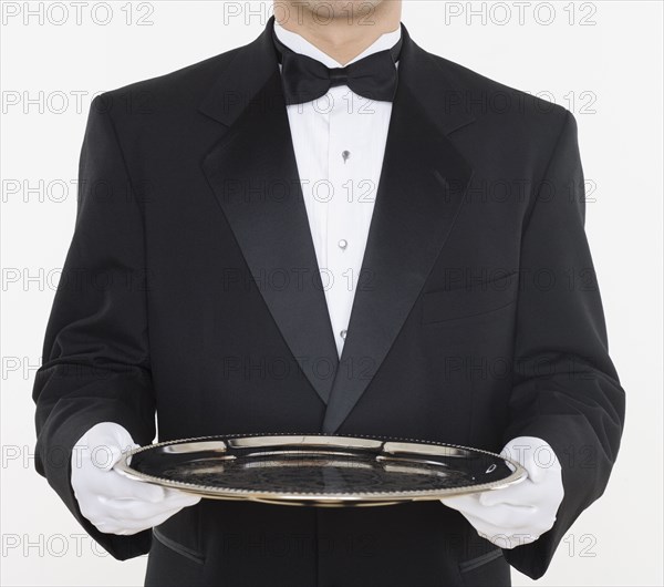 Mid section of male waiter holding tray