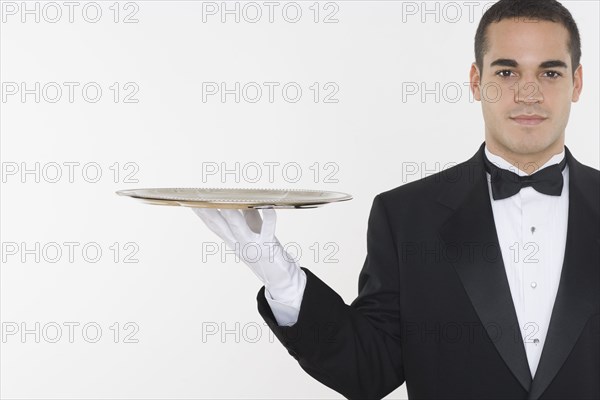 Portrait of male waiter balancing tray