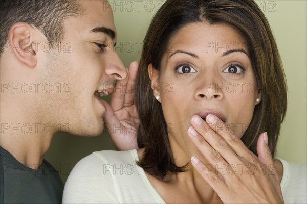 Man whispering into woman's ear