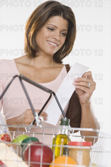 Woman reading receipt while shopping for groceries