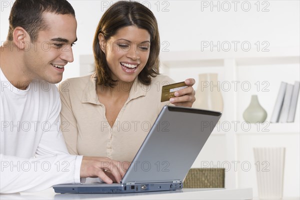 Couple ordering online with credit card and laptop