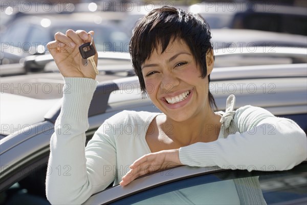 Portrait of woman holding car keys and standing with car door open