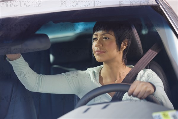 Woman adjusting rear view mirror in car