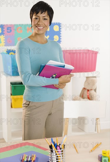 Portrait of woman holding books behind desk