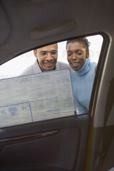 Low angle view of couple looking at sticker on new car window