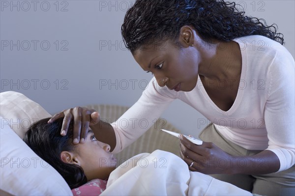 Mother taking daughter's temperature and feeling forehead