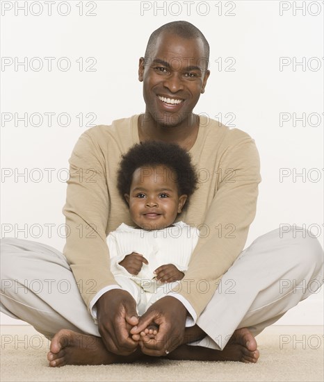 Father sitting cross legged while holding baby daughter