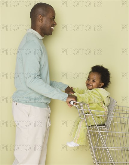 Father shopping with baby daughter in shopping cart