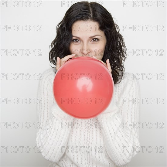 Portrait of woman blowing up balloon