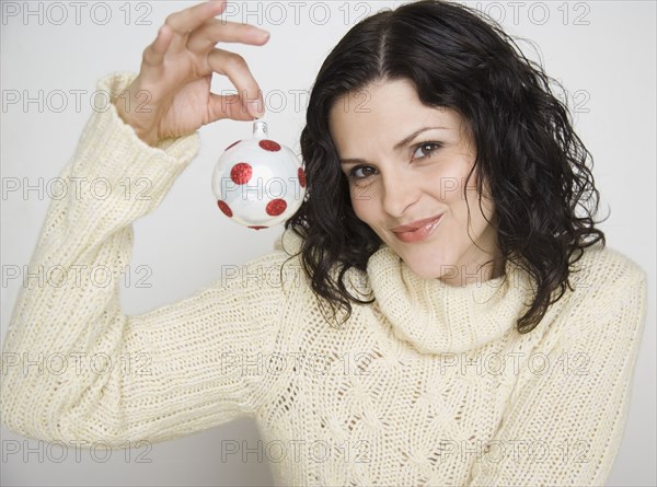 Portrait of woman holding up Christmas ornament