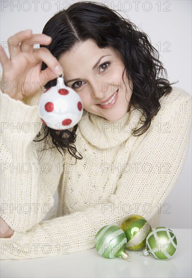 Portrait of woman holding up Christmas ornament