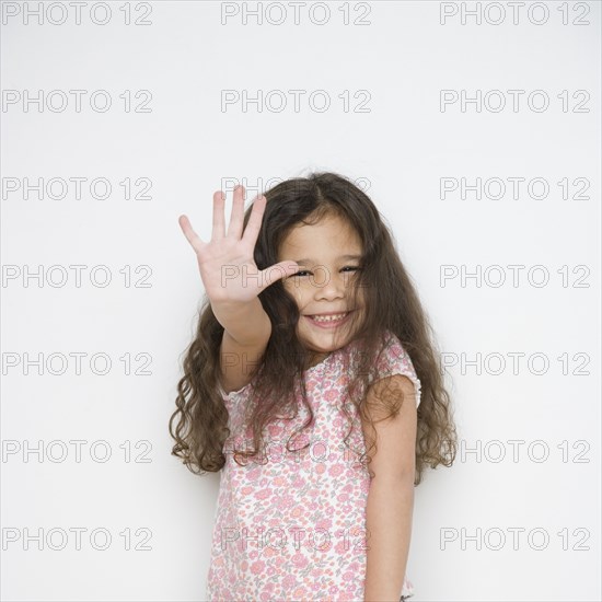 Portrait of young girl holding hand up in front of her