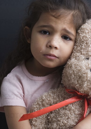 Portrait of girl crying and hugging teddy bear