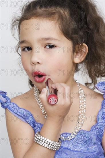 Portrait of girl applying makeup while playing dress up