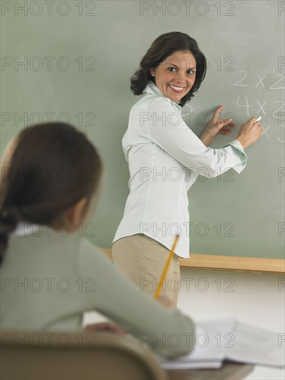 Teacher writing arithmetic on the blackboard