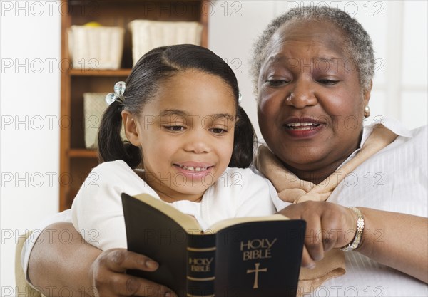 Senior woman reading the Bible to her granddaughter