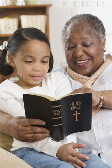 Senior woman reading the Bible to her granddaughter
