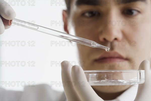 Scientist dropping chemicals into a Petri dish