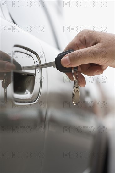 Close up of man's hand unlocking car door with key