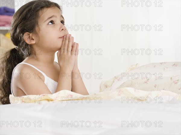 Young Hispanic girl saying bedtime prayers