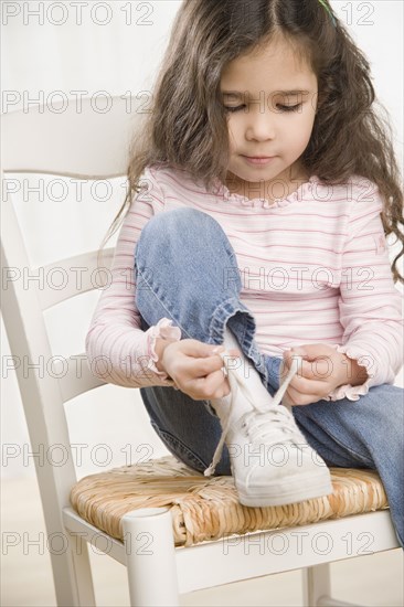 Young Hispanic girl tying shoe