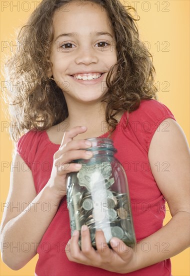 Young girl holding jar full of money