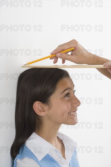 Hispanic girl having height marked on wall