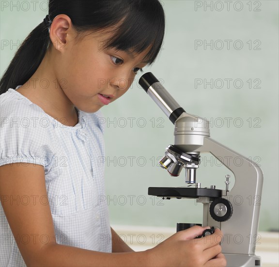 Young Asian girl looking through microscope
