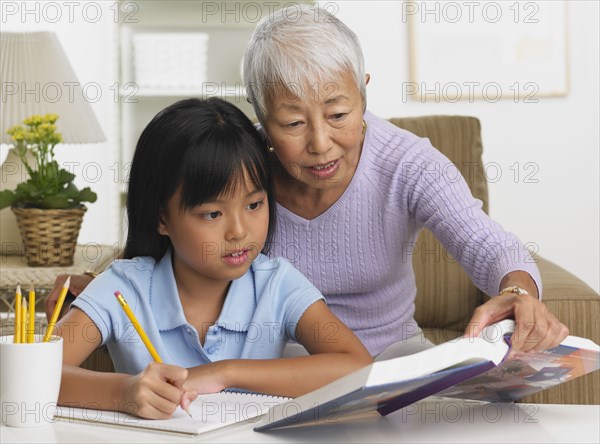 Asian grandmother and granddaughter doing homework