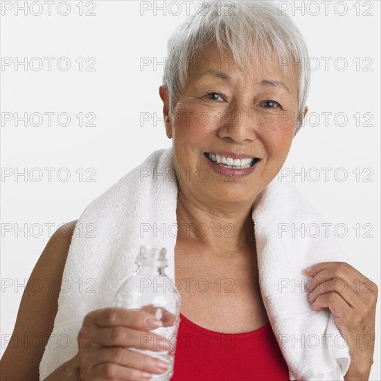 Studio shot of senior Asian woman with water and towel