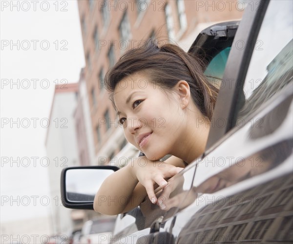 Young Asian woman leaning out of car window