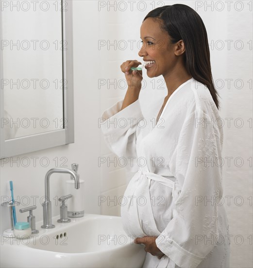 Pregnant African woman brushing teeth