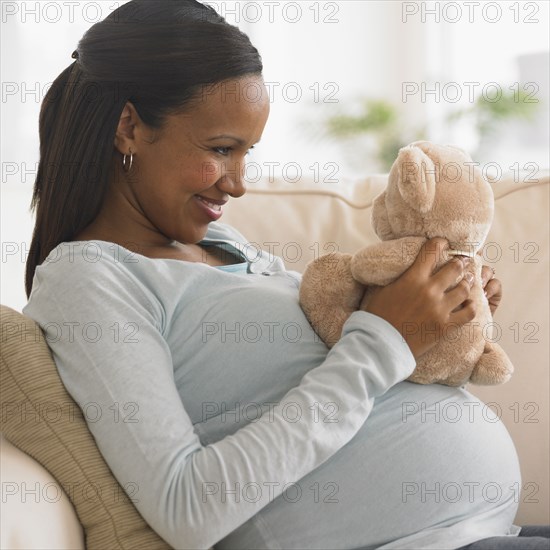 Pregnant African woman hugging teddy bear