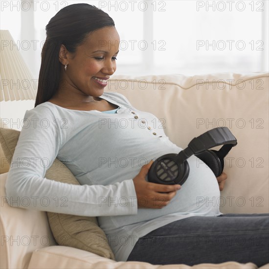 Pregnant African woman holding headphones to belly