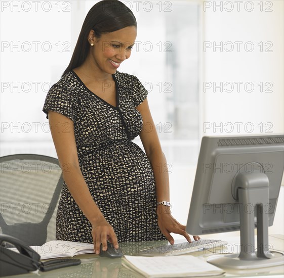 Pregnant African businesswoman at desk