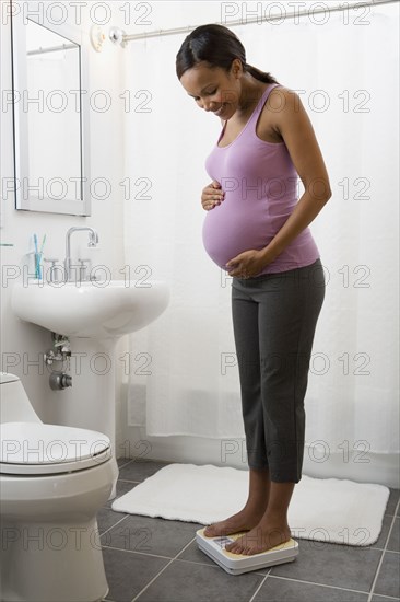 Pregnant African woman standing on scale